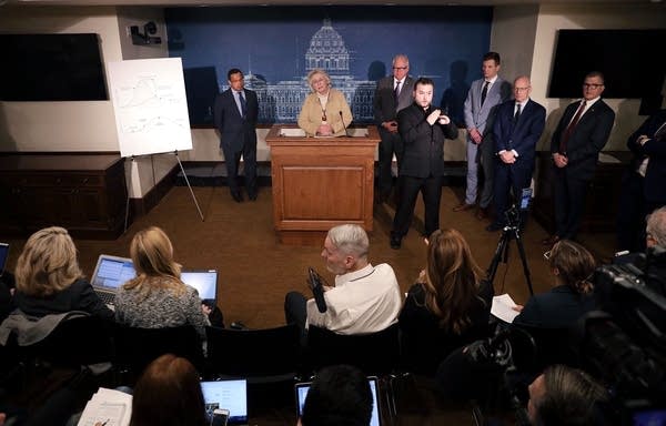 People stand at a podium during a press conference. 