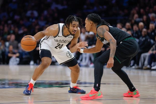 A Nets player and Timberwolves player face off on the court.