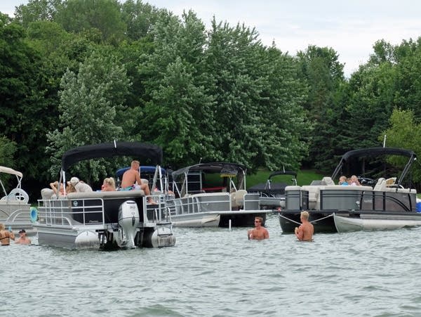 people swim while others sit on a pontoon boat