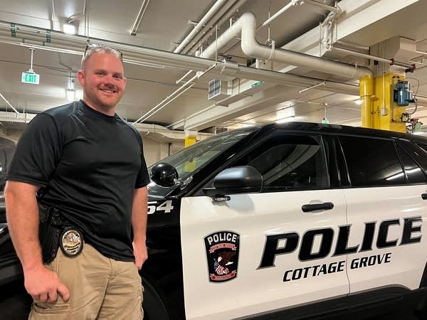 Officer poses by a Cottage Grove police car