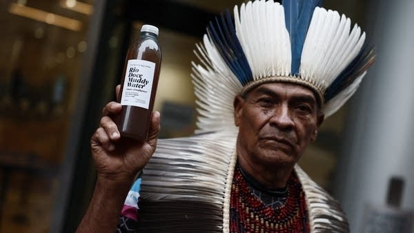 Cacique Bayara, a member of the Pataxos people, holds a bottle of contaminated water from the river Doce, during a victim gathering outside of the High Court in London on Monday.