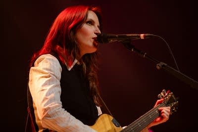 Person playing guitar and singing on stage