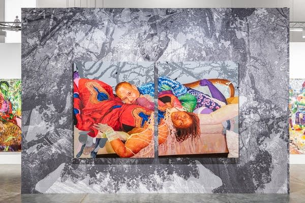 A colorful painting of two people lying down, split into two canvases. It's hanging in front of a larger, black-and-white illustration.