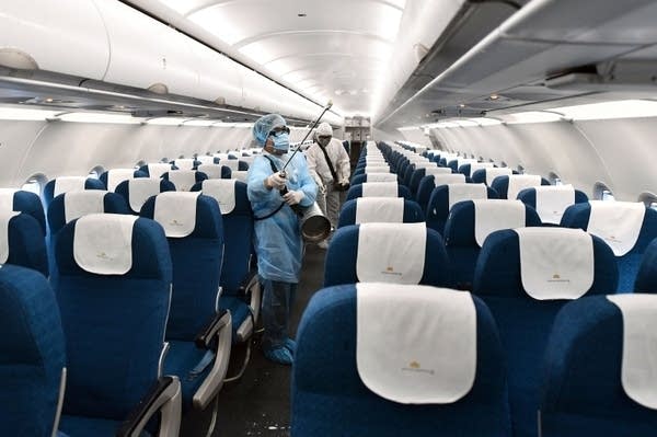 Vietnam Airlines staff wear protective suits as they disinfect a plane at Noi Bai International Airport in Hanoi.