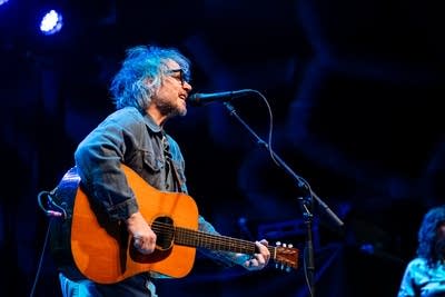 A man sings and plays guitar onstage