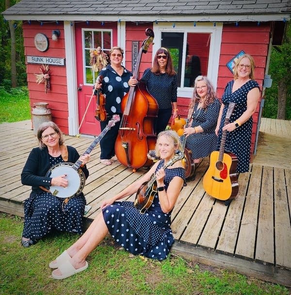 Six musicians pose outdoors while holding their instruments