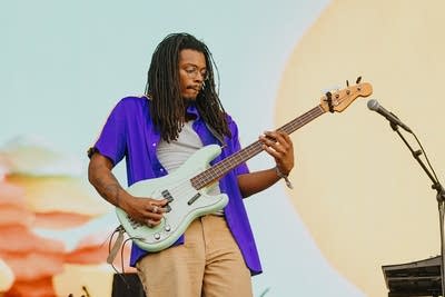 A musician plays bass on a large outdoor stage