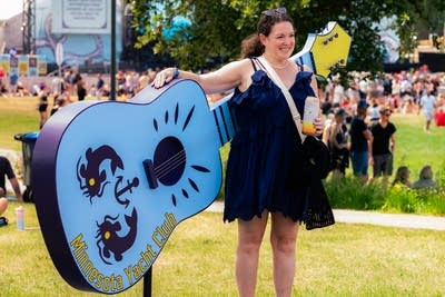 person posing in front of a minnesota yacht club guitar