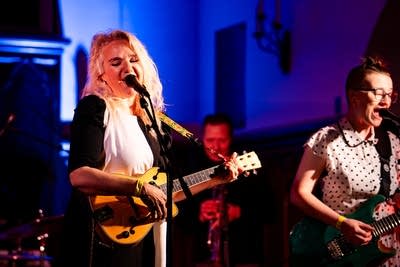 two women singing and playing guitar on stage