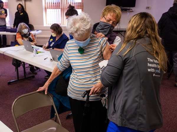 A person in a blue mask gets a COVID-19 vaccine shot.