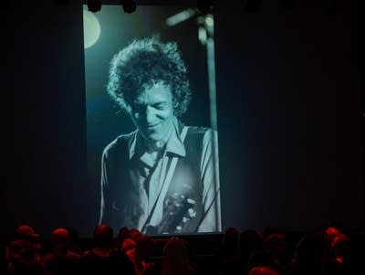 A slideshow of photos of Slim Dunlap shows on a giant screen.