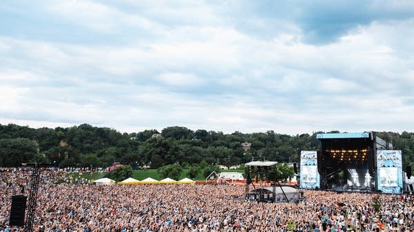 A crowd of people gather for an outdoor music festival.