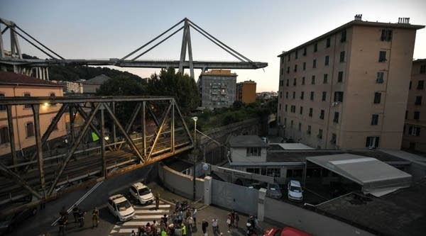 A general view shows apartment buildings under the Morandi motorway bridge in background one day after a section collapsed in Genoa on August 15, 2018. - Nearly 40 people died on August 14, 2018 when a giant motorway bridge collapsed in Genoa in northwestern Italy, with the death toll expected to mount further.