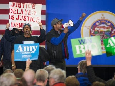 Protesters take the stage at the site of a rally for Sen. Amy Klobuchar