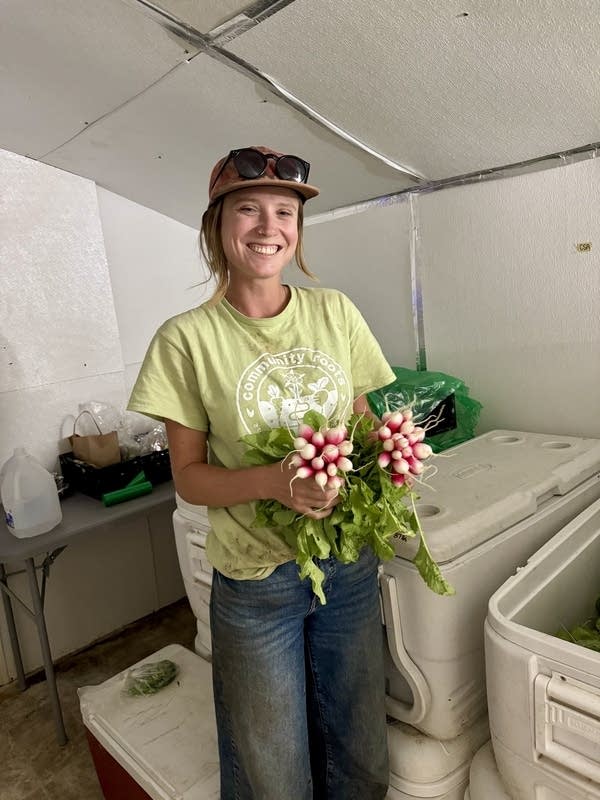 A woman holds a bunch of radishes.