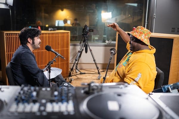 Two people sit in a music studio