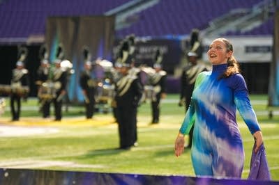A marching band performs on the field of a football stadium.