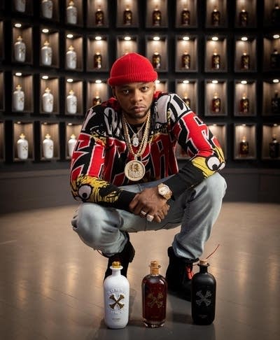 A man in fashionable clothes poses with distilled spirits