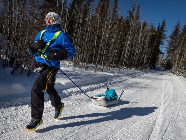 A runner sprints down a snowy trail