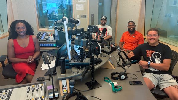 four people smiling in a broadcast studio