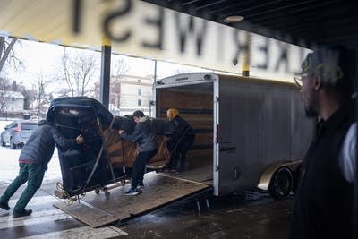 Movers unload a piano from a trailer