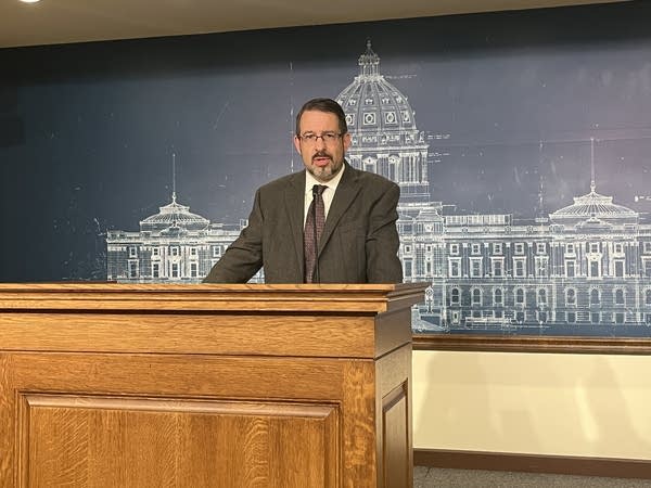 A man stands behind a podium during a press conference.