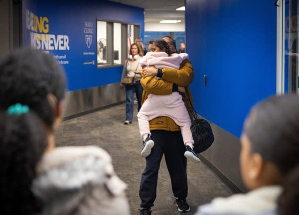 A man picks up a girl to hug her in an airport.