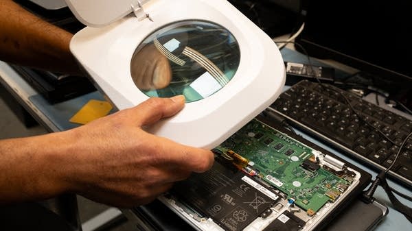 A worker of Kringwinkel, a partnership of companies that collects, repairs, and resells second-hand objects, repairs a laptop on November 17, 2023 in Antwerp, Belgium. 