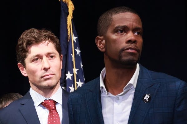 Two people speak during a press conference.