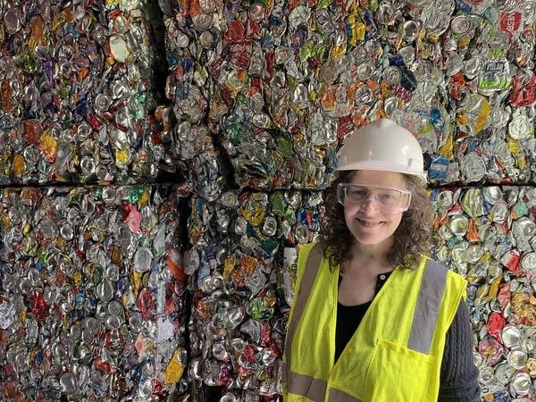 a woman stands in front of baled recycling