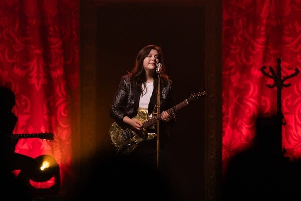 Person playing guitar and singing on stage