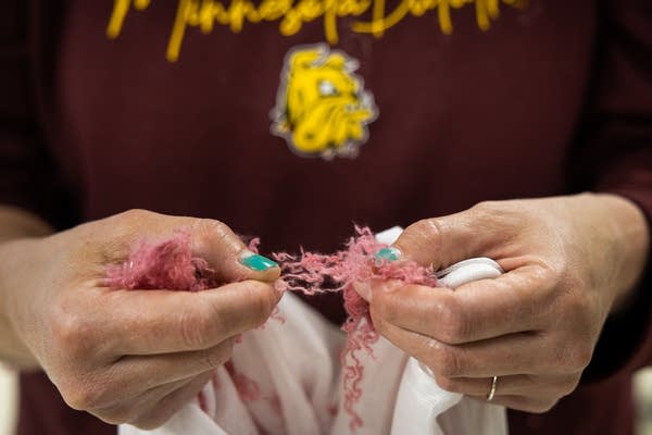 A woman holds strands of shredded fabric