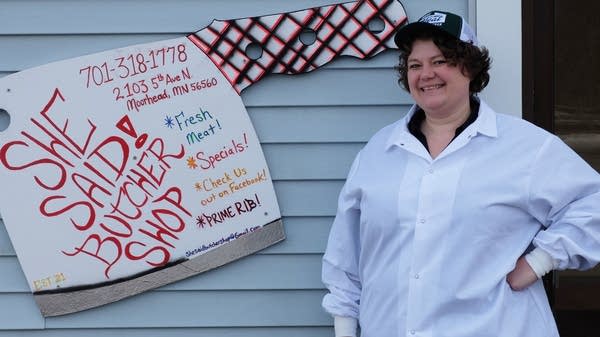 a woman stands next to a sign