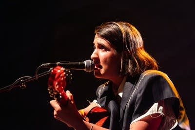 A musician sings and plays guitar onstage