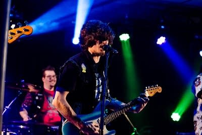 A musician sings and plays guitar onstage