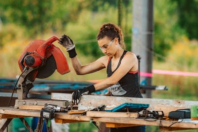 A woman works on an art piece with a buzzsaw.