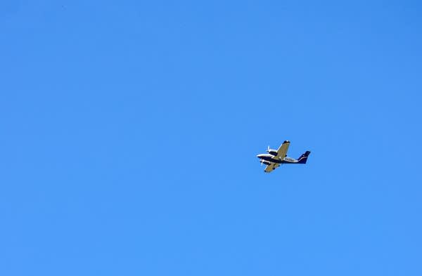 A small plane flies in a bright blue sky.l