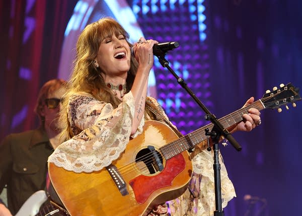 A musician sings and plays guitar onstage