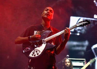A man sings and plays guitar on an outdoor stage