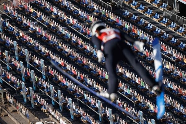 A ski jumper soars through the air above cardboard cut-outs placed in the stands to represent spectators during the trial round of the women's HS106 ski jumping event at the FIS Nordic Ski World Championships in Oberstdorf, southern Germany, on February 25, 2021. 