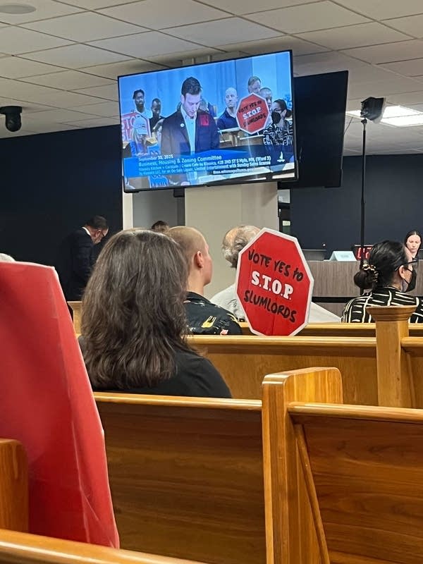 People sit in pews to attend a public hearing.