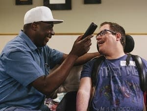 Caregiver Francis Ebuchu holds the phone for Jimmy Mossow