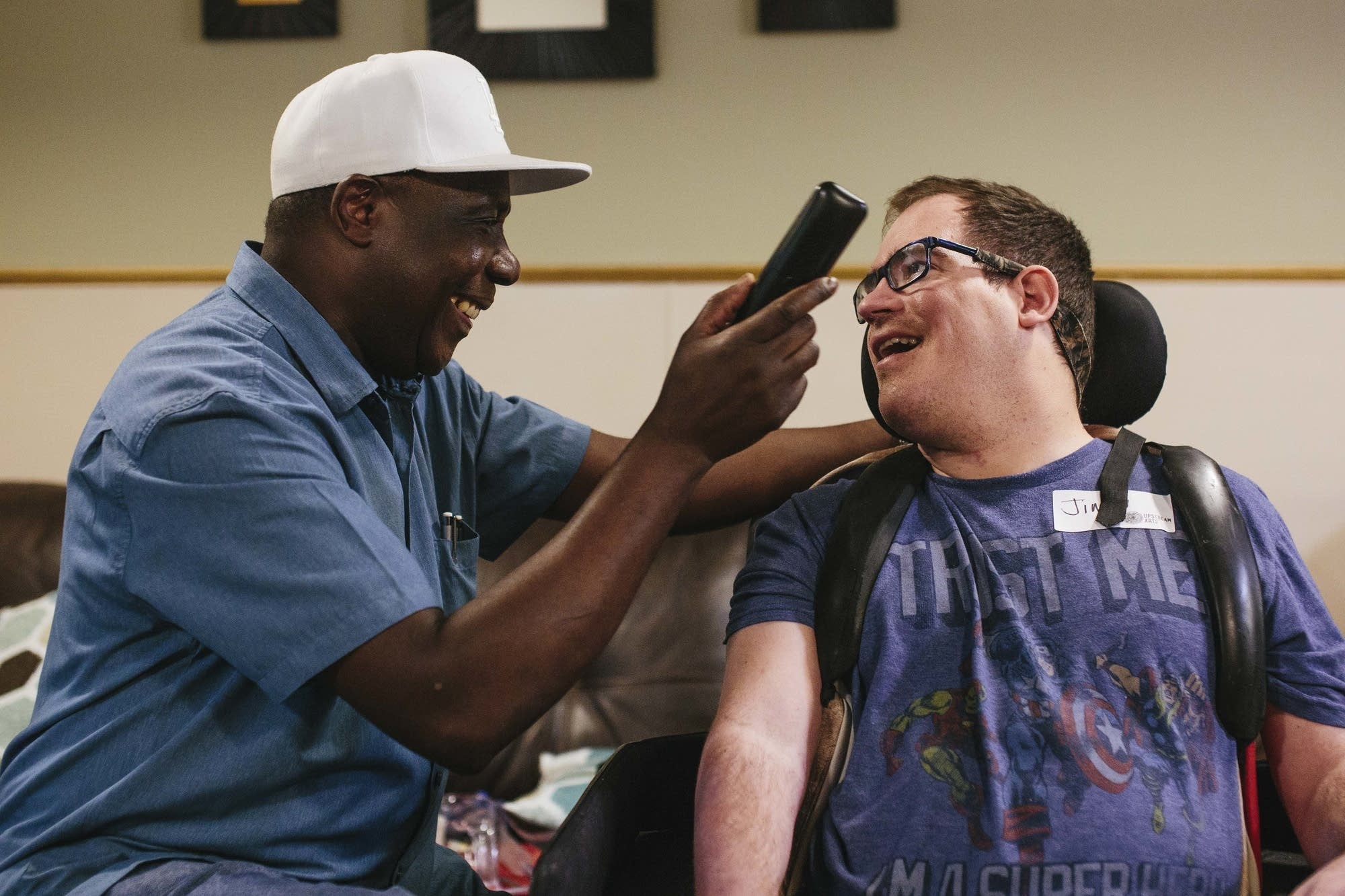 Caregiver Francis Ebuchu holds the phone for Jimmy Mossow