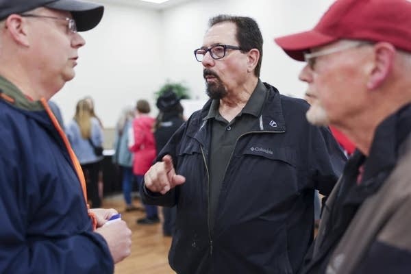 Three people talk during a public meeting.