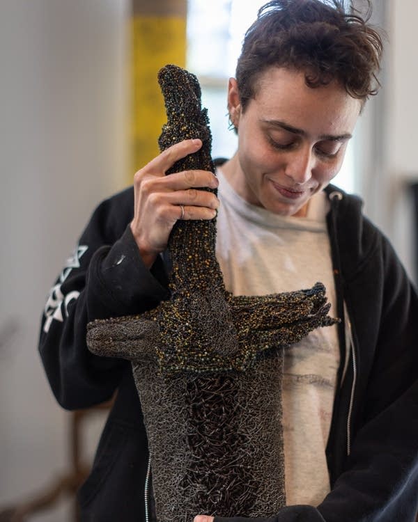 A person cradles a sculpture 