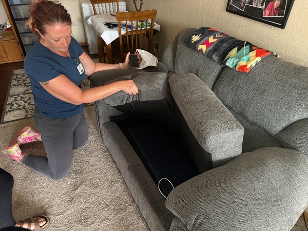 A woman makes adjustments to a couch in her living room.