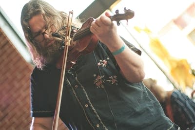 A musician plays violin in a taproom