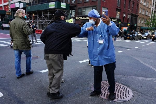 A medical worker elbow bumps a passerby in New York City.