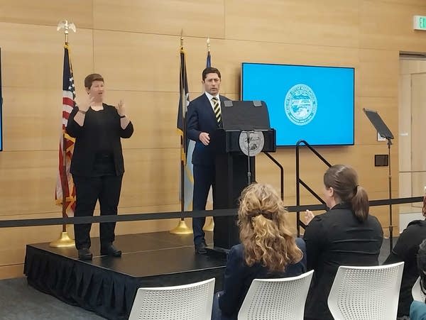 A man stands at a podium in front of an audience