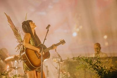 A musician sings and plays guitar on a large outdoor stage